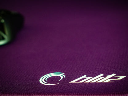 Close up of the LA ONDA Blitz mouse pad in the colour purple. The logo is in focus. There is a Razer Viper Mini Signature Edition on the pad, out of focus.